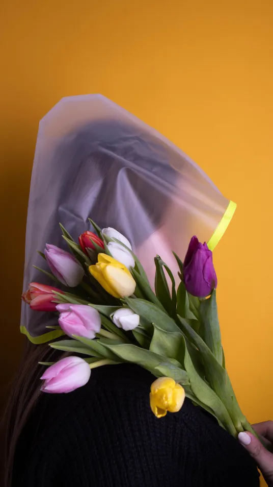 Une femme avec une capuche transparente et des fleurs des couleurs différentes