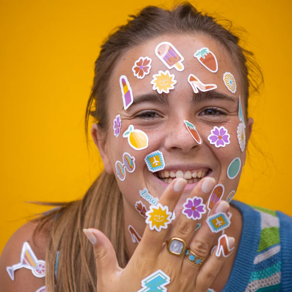 Une jeune femme avec des stickers sur son visage enjouée